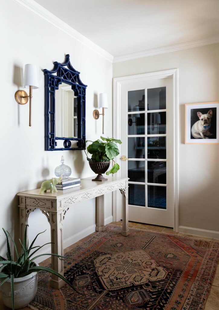 Chinese Chippendale console and a vintage oushak rug make for a stellar Entry. A cute french bulldog painting graces the walls. Elizabeth Ryan highland park texas
