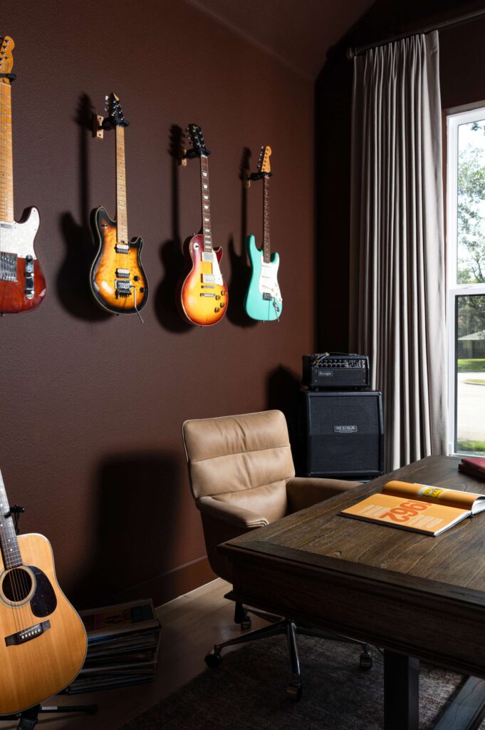 Oxblood painted wall with colorful electric guitars displayed as art