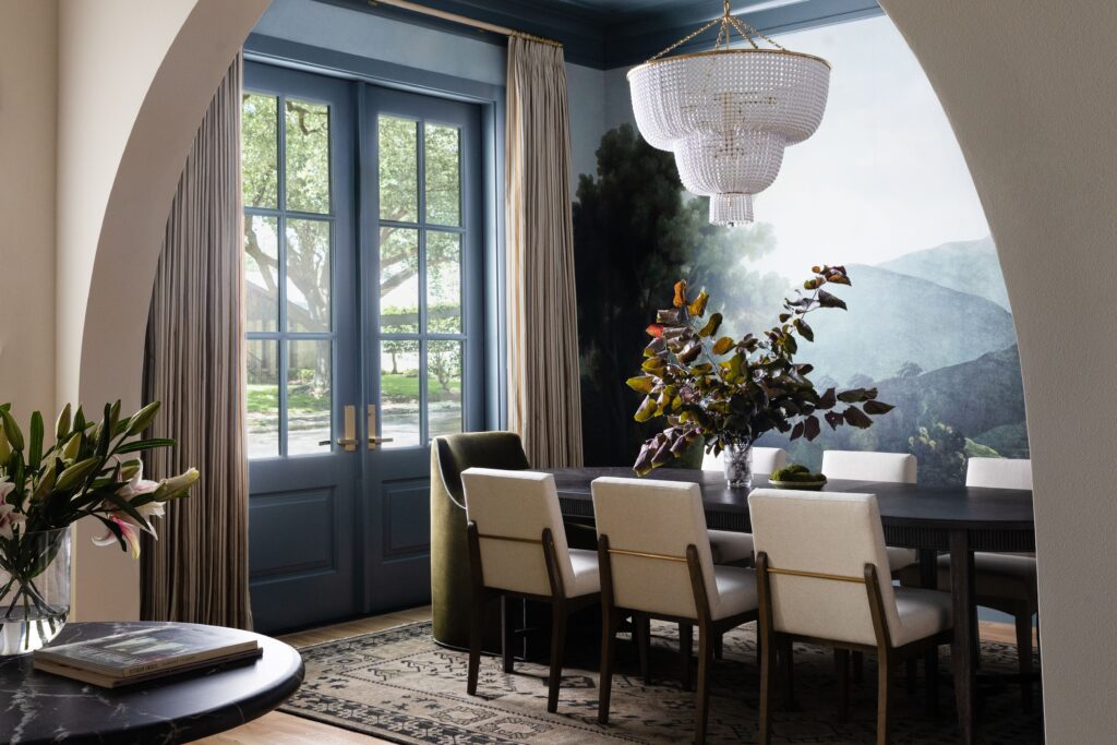 Dining room with a hand-painted landscape mural, beaded chandelier, and custom drapery framing French doors