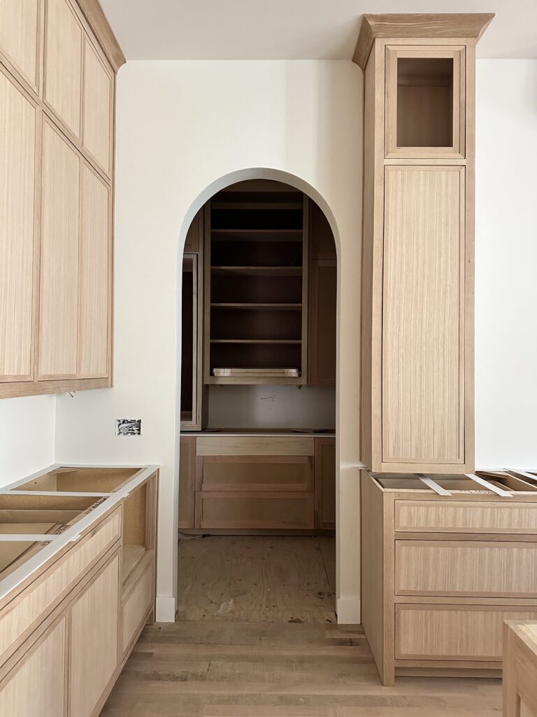 Unfinished pantry with raw wood shelving and an arched entry, captured mid-build in Richardson, Texas